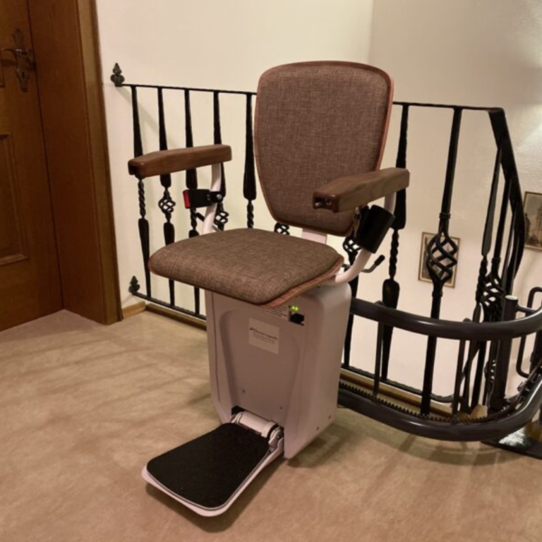 Curved stair lift with a folded seat installed on a villa staircase